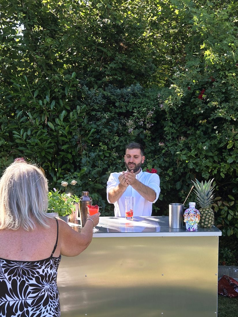 Salute bartender serving a cocktail to a guest at a garden party