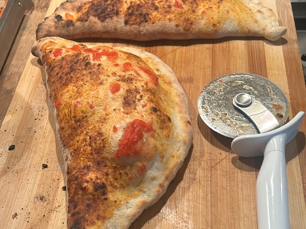 Two freshly baked Salute calzones on a wooden board